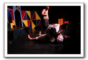 Sean Casey as Capitano in the background with Brian Kraemer as Arlecchino on top of Chas Saphos, playing Pulomo